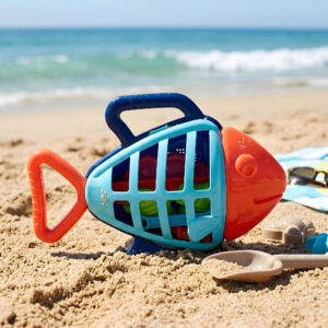 Beach toy set with a fish-shaped carrier set on a beach.