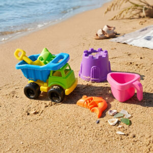 Plastic toy set laid out on a sunny beach.
