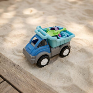 Beach toy in a shape of a dump truck with 19 accessories loaded in its bed. The set is placed on a beack or a sandbox type of environment.